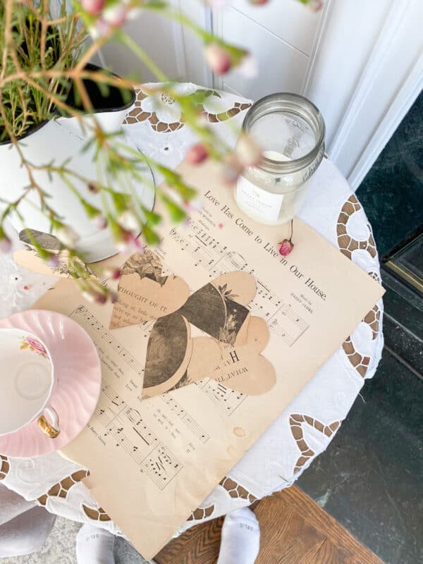 photo of vintage sheet music, with hearts cut from an antique books a candle and a tea cup