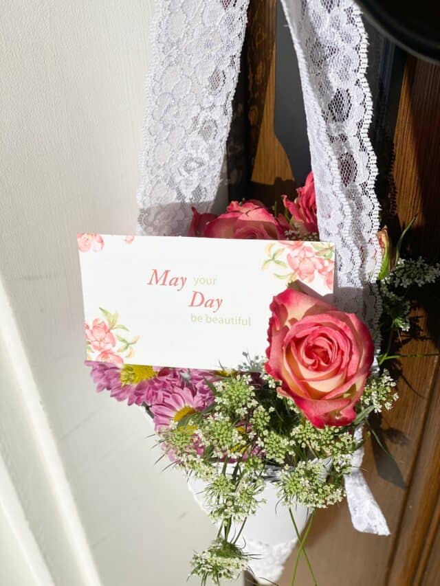 May Day basket with flowers and a card hanging on a front door.