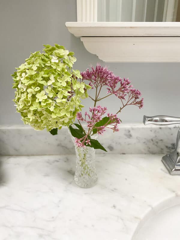 small Waterford vase with flowers in bathroom on marble countertop