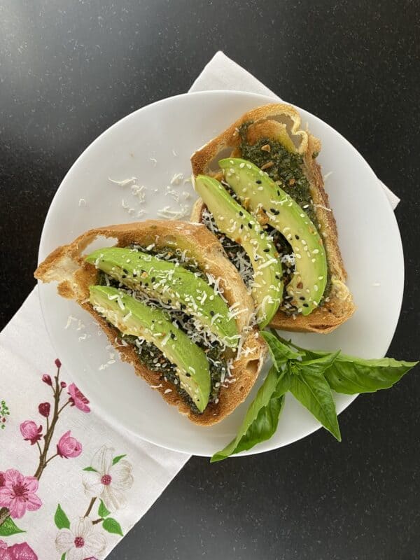 photo of toast with pesto sauce, sliced avocado and everything but a bagel seasoning on top.