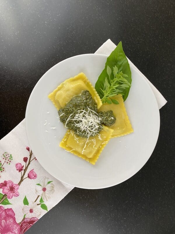 photo of ravioli on a plate with pesto sauce over it.