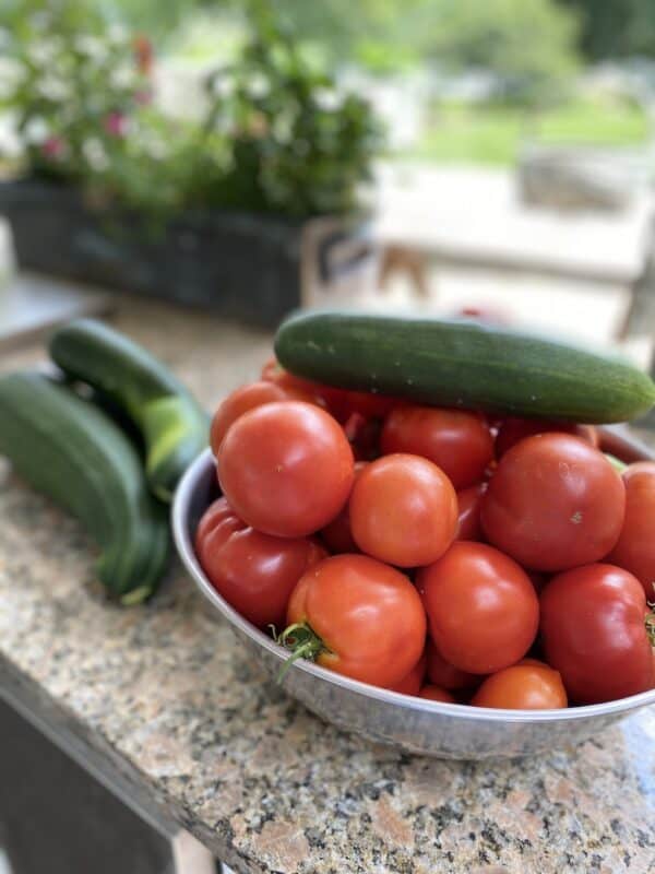 countertop with a bowl full of tomatoes and cucumbers. Preparing for preserving for fresh tomato flavor all year long
