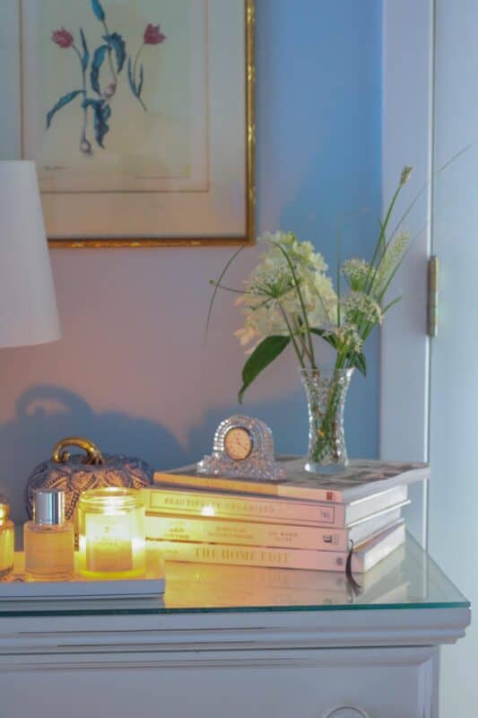 picture of my nightstand with a candle, book and flowers for my post of how to make a cozy bedroom.