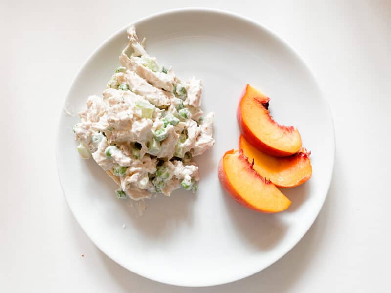 chicken salad on round plate with peaches on the side is a great fall salad