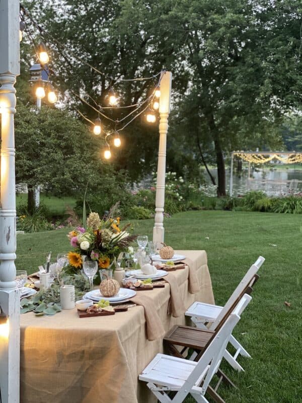 harvest tablescape with swagged Edison lights draped from vintage porch posts on either side of the table