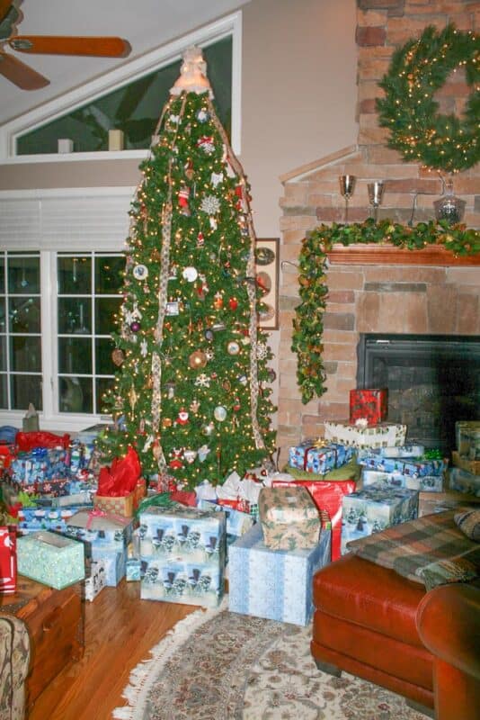 christmas tree next to a fireplace with lots of presents under it