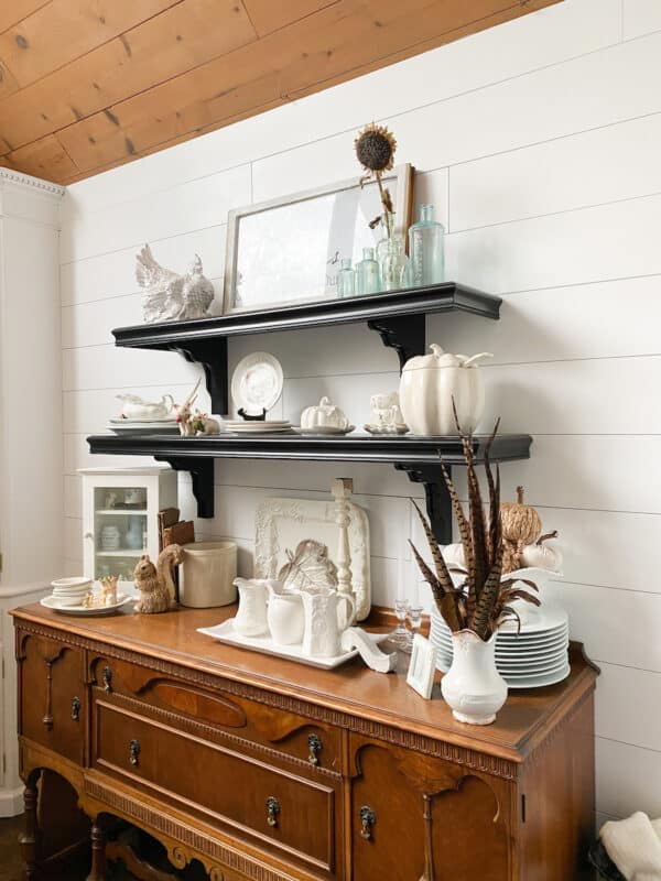 black open shelves on shiplap wall with medium wood antique sideboard below