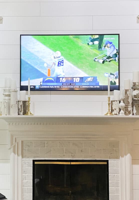frame tv over fireplace with a football game playing. The placement is great for a party