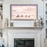 Samsung Frame TV above fireplace on shiplap wall with pictures of a western black and white scene on the tv