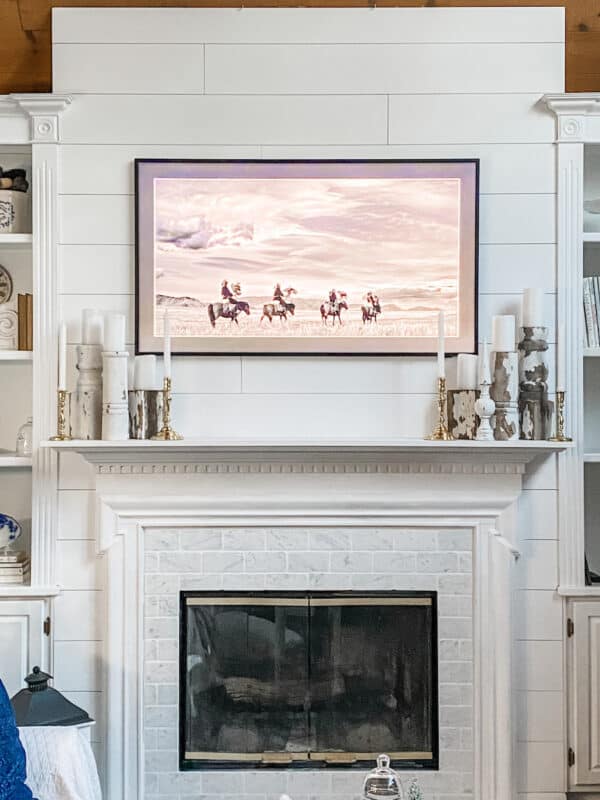 Samsung Frame TV above fireplace on shiplap wall with pictures of a western black and white scene on the tv