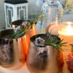 copper glasses with cranberry Moscow mules on table with candle