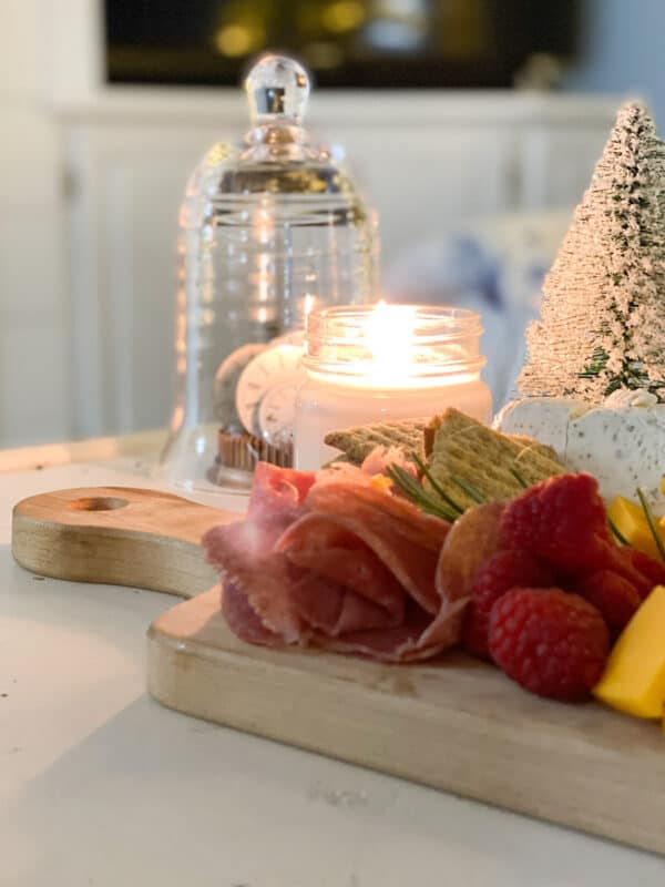 charcuterie board on table with candle for holiday cocktail time