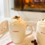 white mugs with baileys and coffee in front of the fireplace