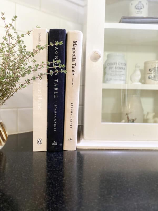 Three cookbooks lined up on my kitchen countertop next to a small vintage spice box