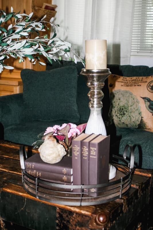Little tray on table in front of sofa in guest room with books, candle and flowers