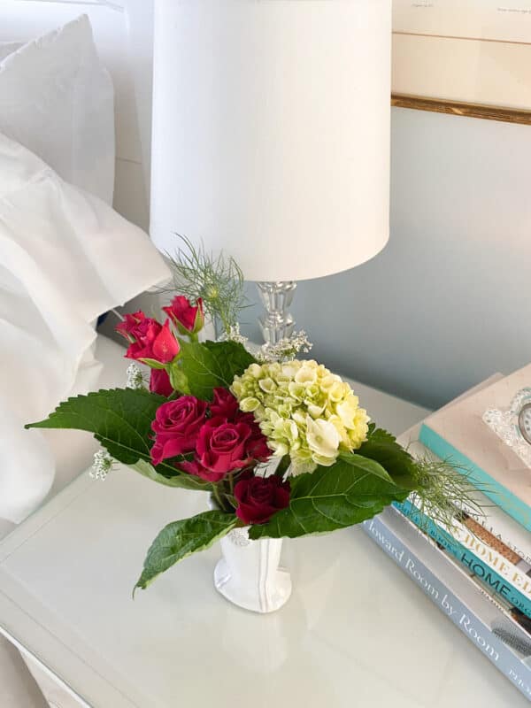 vase with flowers on nights stand next to bed