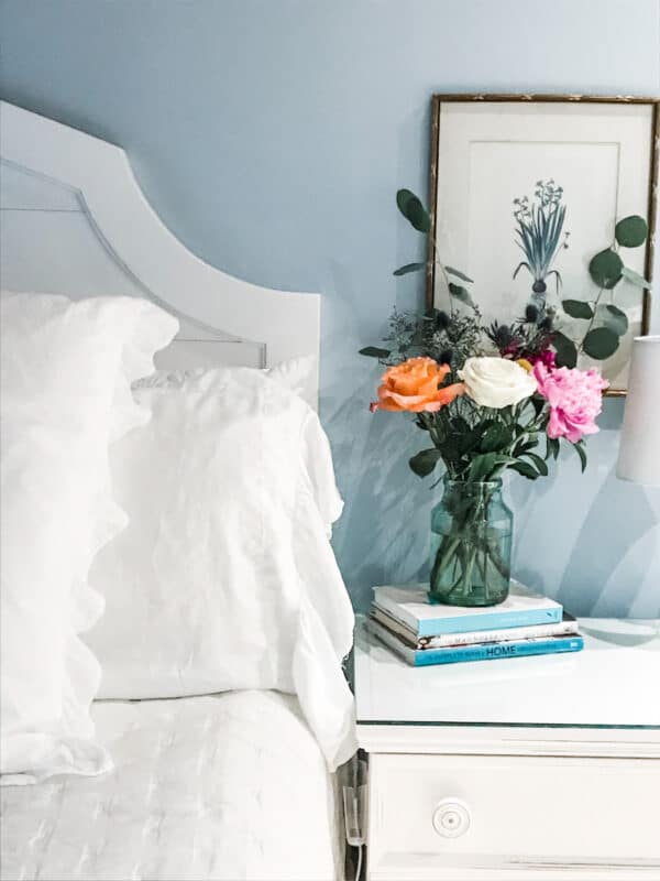 vase with flowers on nights stand next to bed