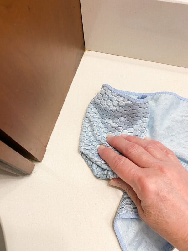 picture of my hand cleaning the bathroom counter tops with a microfiber cloth