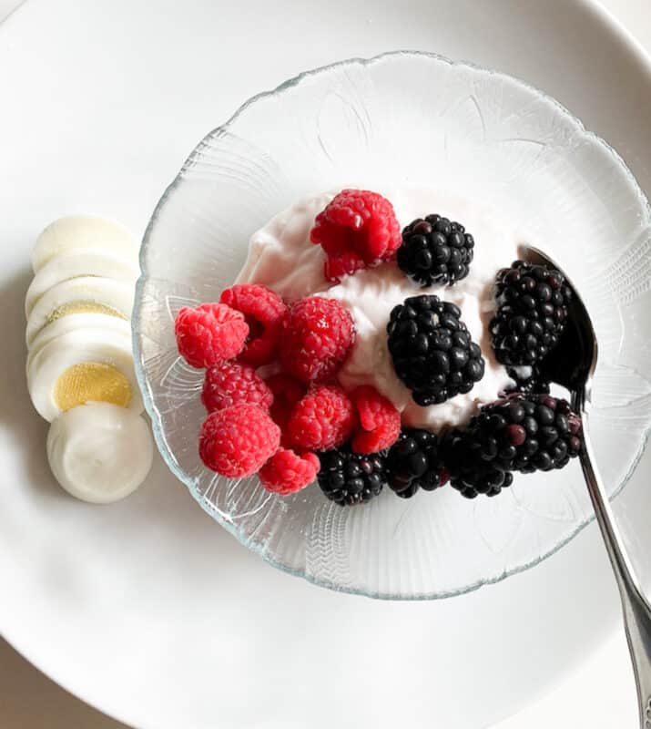 yogurt with berries and a hard boiled eggs for breakfast on the monthly meal planning guide