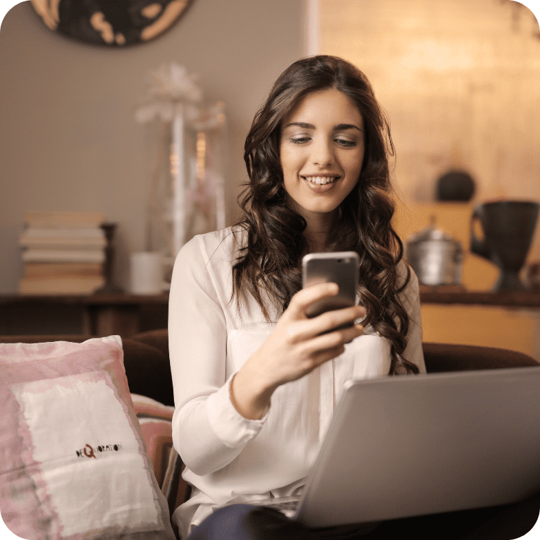 stock picture of a girl on her smart phone sitting in front of a computer in a room