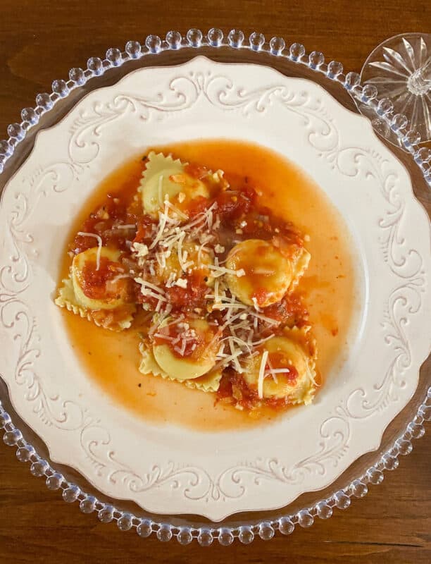 Cheesy Lobster Ravioli with Tomato Sauce on White plate, set on a dark wood table