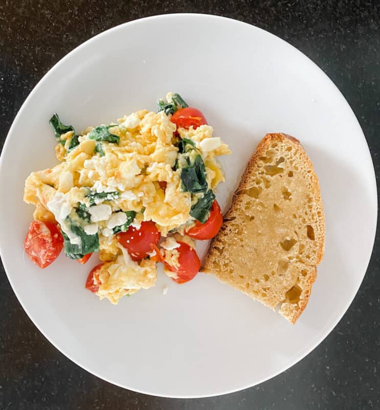 scrambled eggs with tomatoes, spinach and feta cheese with a slice of sour dough toast are part of my monthly meal planning guide