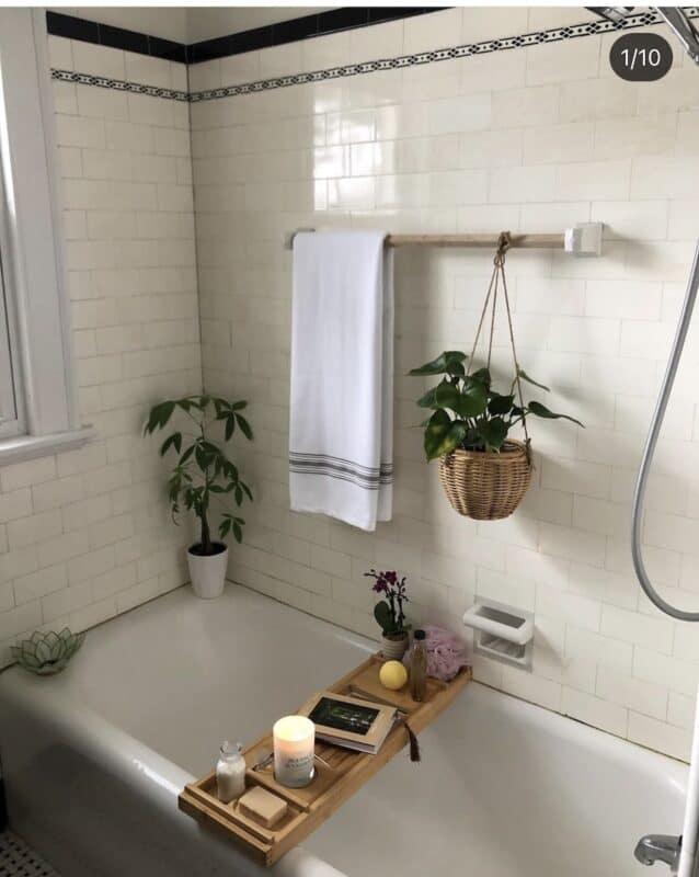 Picture of client bathroom after organization. Vintage white tub with vintage subway tile. plants to freshen up the space and a tub tray with a candle, book and soaps on it.