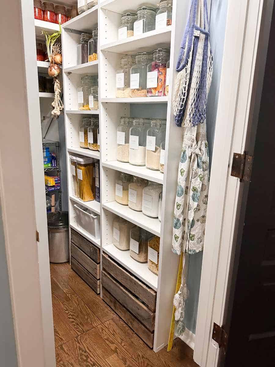Current pantry under the stairs with pallet boxes with hidden wheels on the floor of the pantry