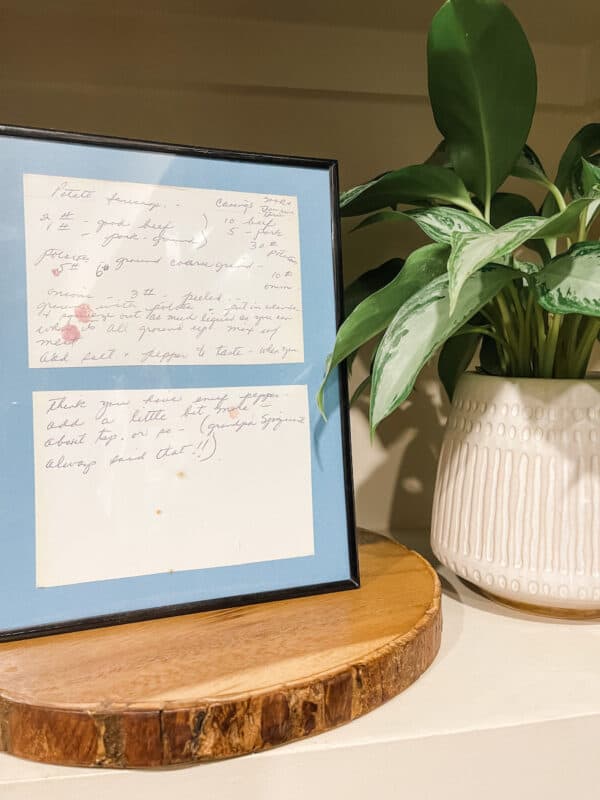 a framed old recipe from grandma on a wooden block next to a plant in a nook in the kitchen