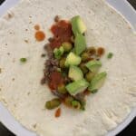 picture of my unique yummy taco recipe. flour tortillas topped with browned ground beef, tomato sauce, chopped green onions, green olives and avocado