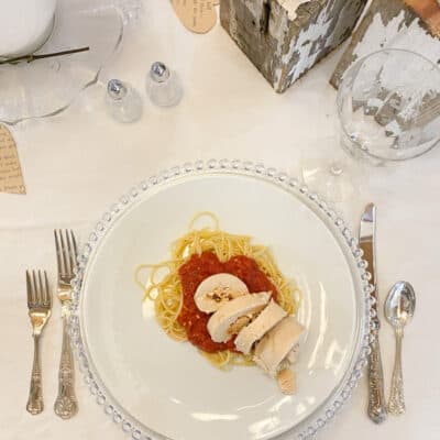 stuffed chicken breast over spaghetti and marinara sauce on a white plate set on a table ready for dinner