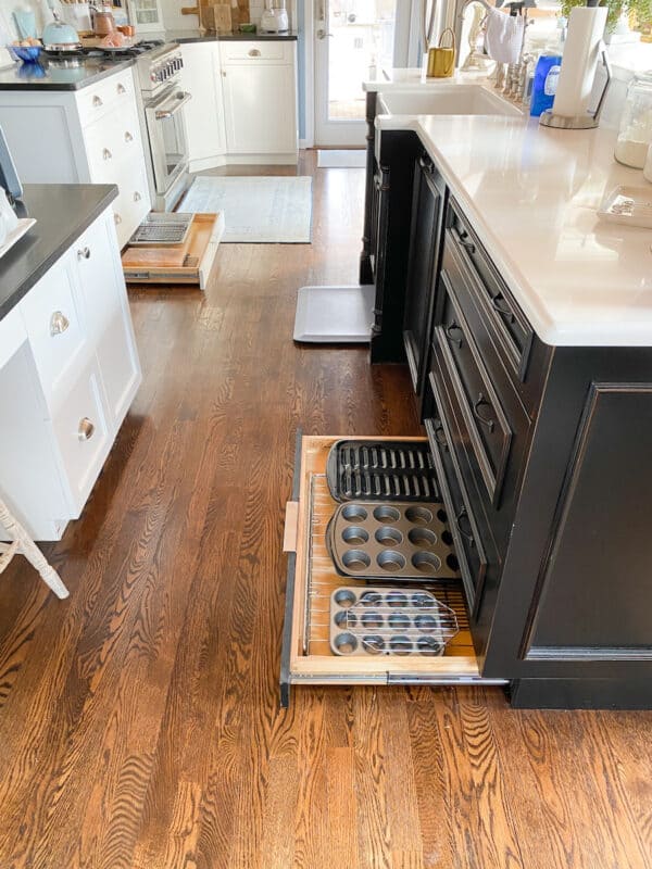 picture of a kitchen with the hidden storage in the toe kick of a kitchen cabinets open