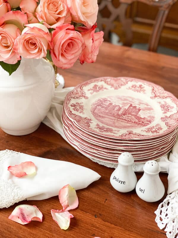 beatiful pink roses with pink vintage plates stacked on a table