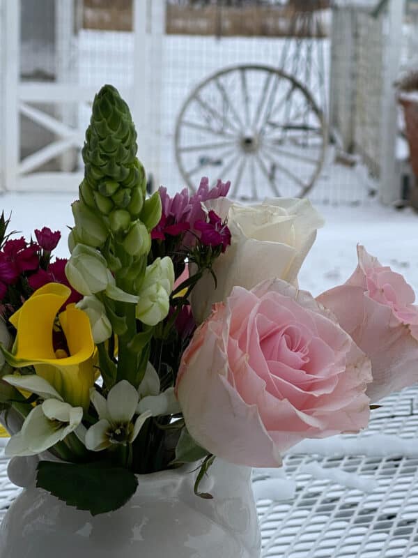 sweet Valentine's Day floral arrangement on an outdoor table with a snowy yard in the background