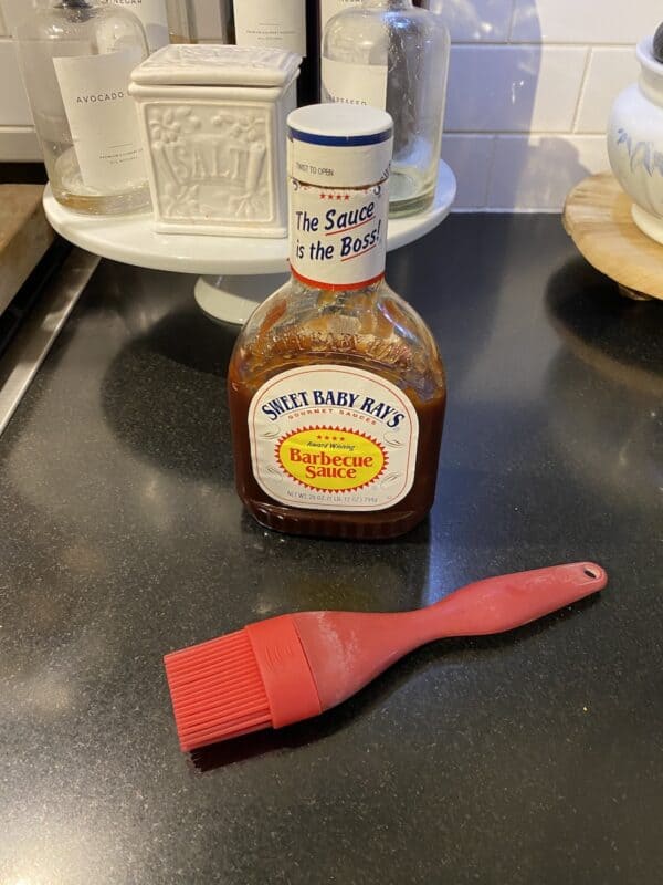 Bottle of Sweet Baby Ray's Original BBQ Sauce on counter top with a silicone basting brush