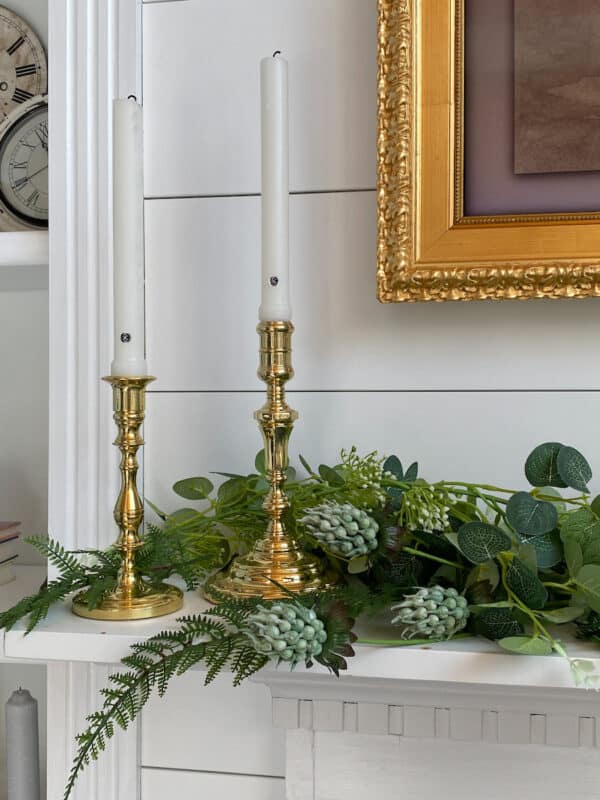 Spring Refresh with some light faux greenery on the mantel and brass candle sticks with white candles