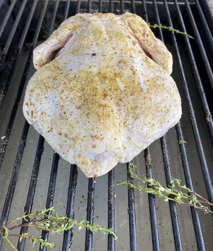 The brined and seasoned chicken on the grates of the grill