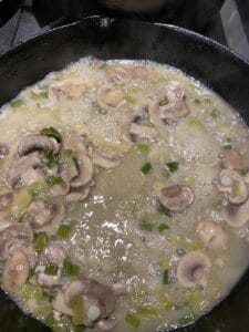the beginning of the sauce for easy creamy chicken marsala. The broth and wine have been added to the skillet with the mushrooms and green onions