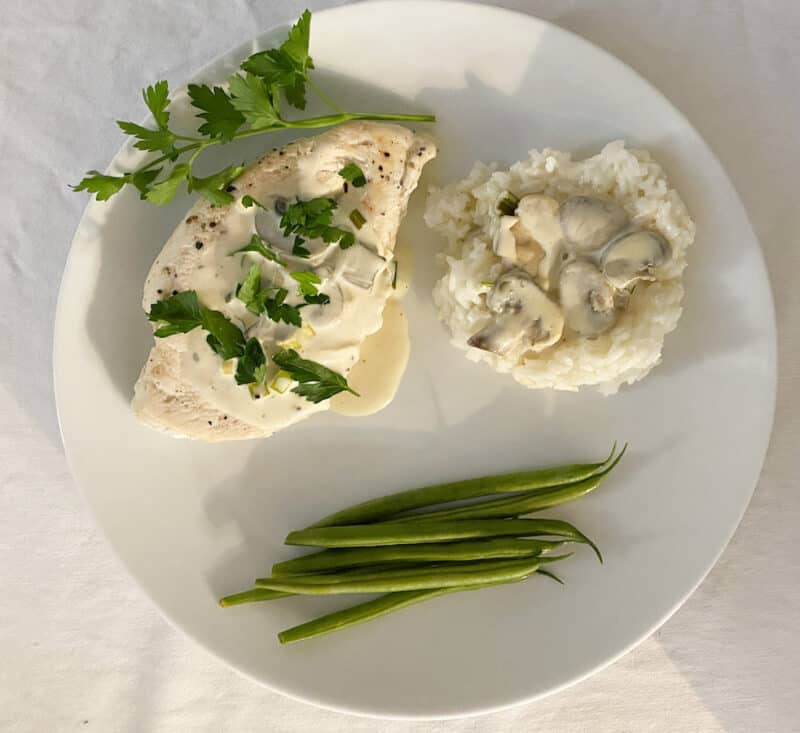 white plate with easy creamy chicken marsala, rice with additional sauce on top and steamed green beans.