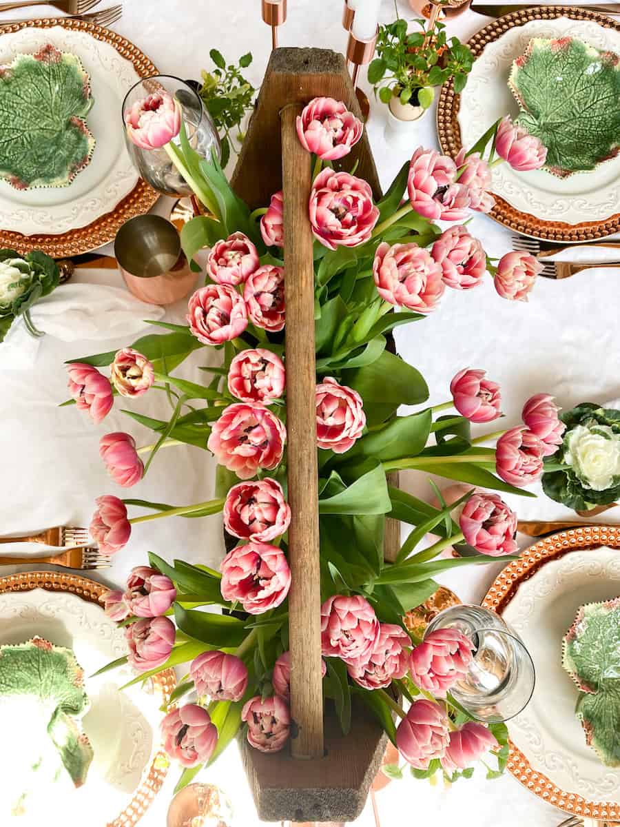 easter table shot from overhead with a vintage toolbox filled with pinkish orange rose tulips