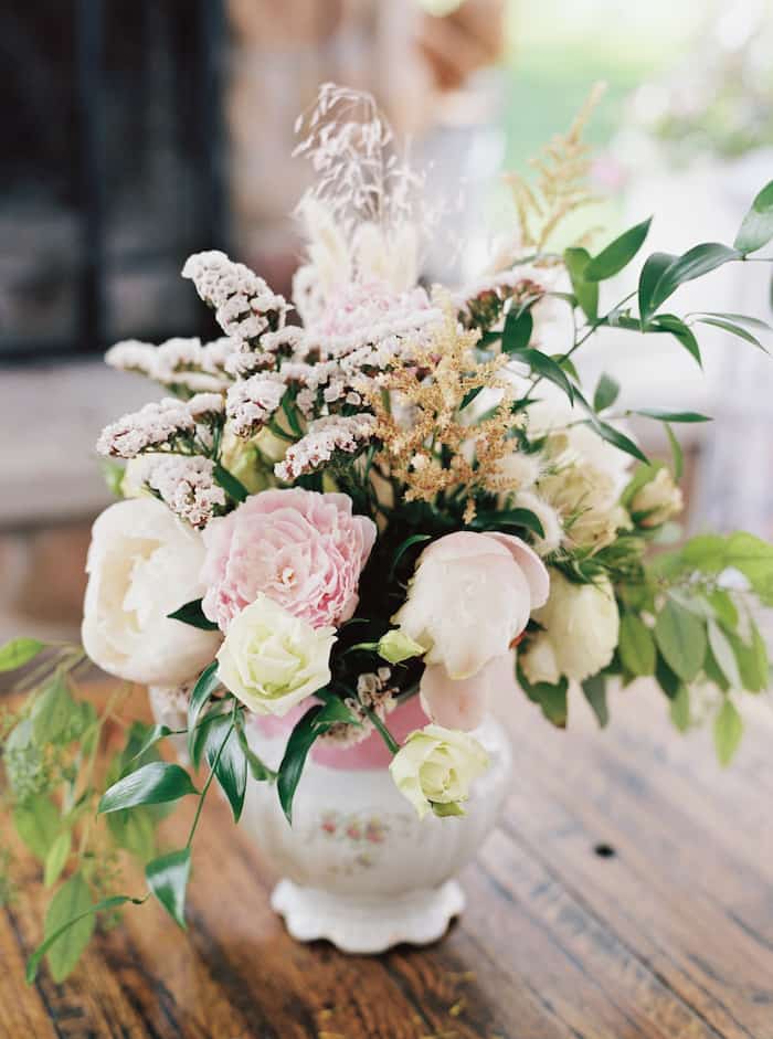 a beautiful bouquet of pink and white flowers with greenery in a vintage pitcher for our covid wedding