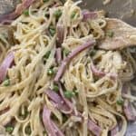 mixing the ham and pea mixture with the pasta and the sauce ingredients in a large mixing bowl