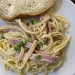 lazy day ham & pea pasta recipe plated on a white plate with a slice of French buttered bread
