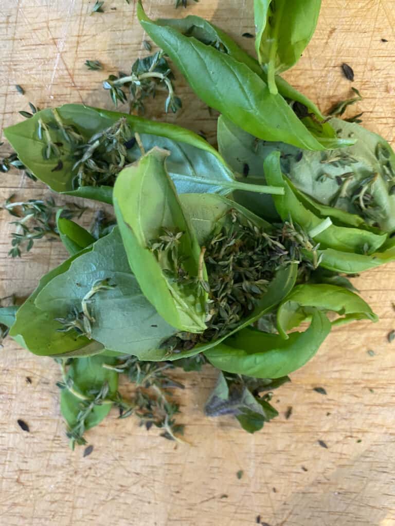 Fresh basil, thyme and oregano ready to be chopped for homemade salad dressing
