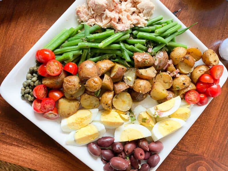 A white platter with the fixings for salad niçoise. This would also make a great 4th of July summer salad dish