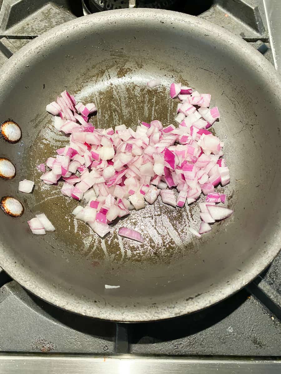 red onions sautéing in oil in a small fry pan