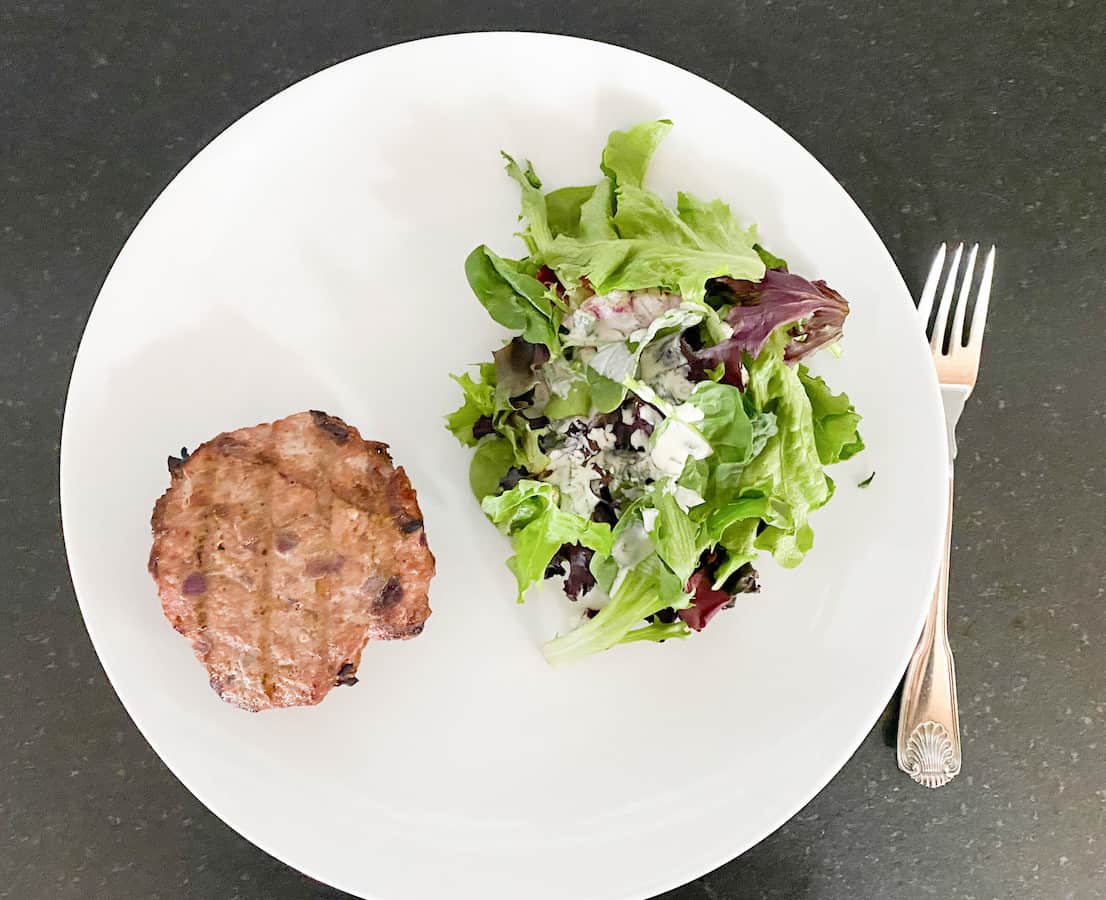 turkey burger with no bun on a plate with a salad and ranch dressing