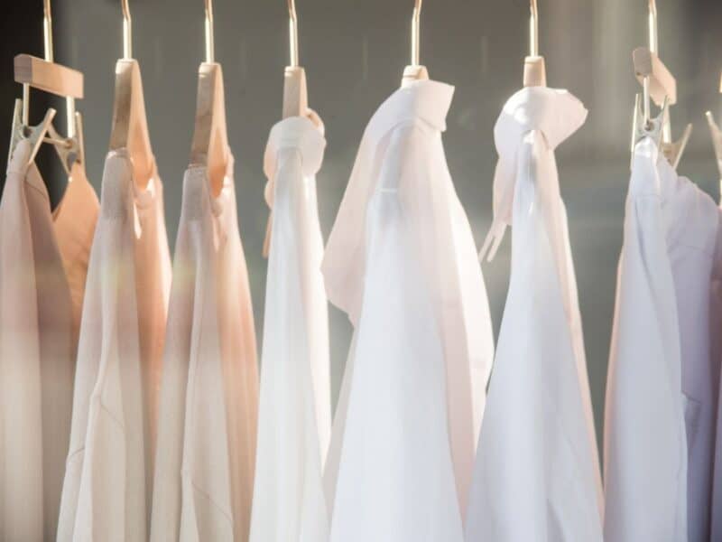 a picture of a closet with white and pink clothes hanging.