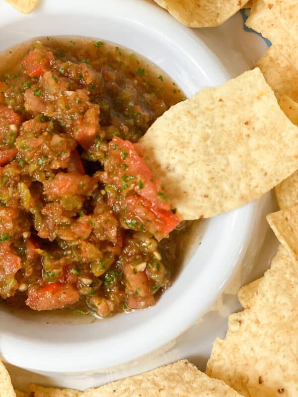 picture of my healthy restaurant style salsa with chips. One of the chips is dipped into the salsa
