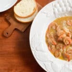 white serving bowl with cajun butter sauce and shrimp